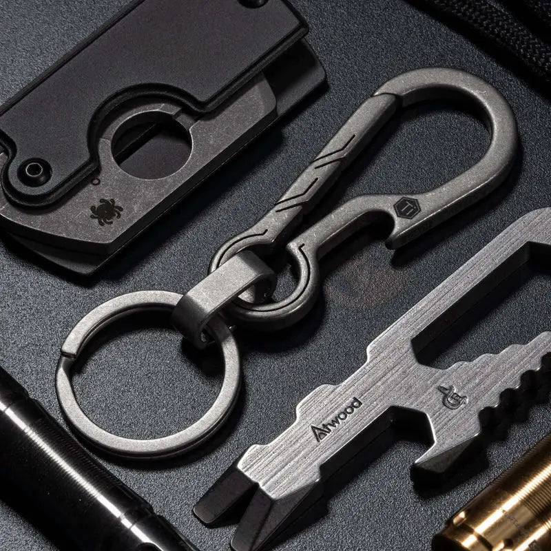 KeyUnity KM01 титаниев EDC ключодържател с клипс и ключов обръч, показан в EDC комплект с мултитул, фенерче и други аксесоари